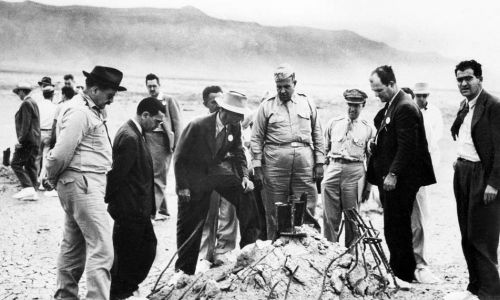 Роберт Оппенгеймер (третий слева, в светлой шляпе) и генерал Лесли Гроувс (рядом) с наблюдателями за испытанием Тринити — первым техногенным ядерным взрывом, 16 июля 1945 года на военном полигоне в Нью-Мексико. Фото: United States Army Signal Corps - Общественное достояние, Wikimedia Commons 