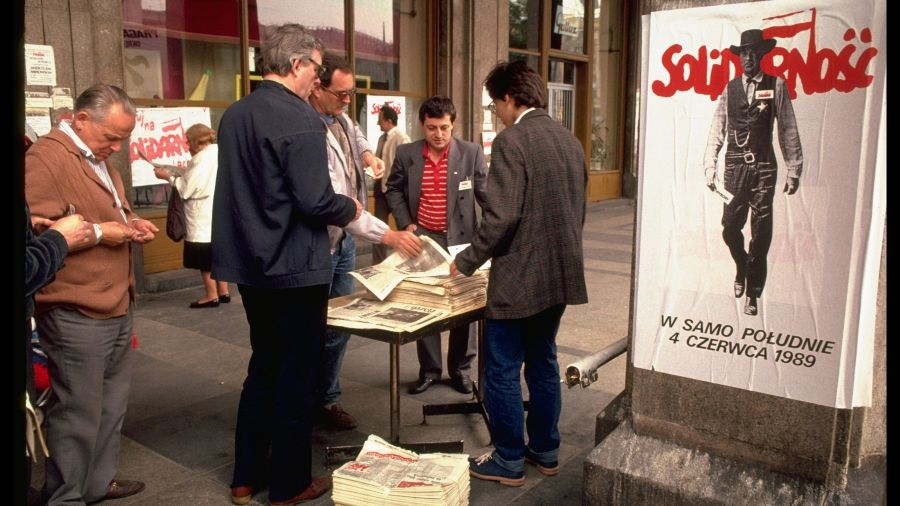 Do głosowania w 1989 r. zachęcał plakat z Garym Cooperem w roli szeryfa Willa Kane’a w westernie „W samo południe”, który w pojedynkę bronił ludzi przed bandytami. Film uważano za alegorie relacji USA – komunizm z lat 50. Na zdjęciu sprzedaż specjalnych wydań opozycyjnych gazet, które donosiły o zdecydowanym zwycięstwie Solidarności. 6 czerwca 1989 r. Fot. Chris Niedenthal/The LIFE Images Collection / Getty Images