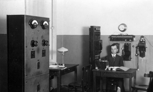 Fragment amplifikatorni, przy stole siedzi kierownik techniczny radiostacji. Fot. Jan Bułhak/IKC/NAC