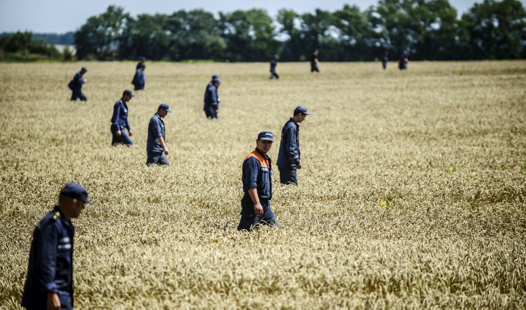 Працаўнікі Дзяржаўнай службы надзвычайных сітуацыяў Украіны шукаюць целы загінулых ў полі ля месца катастрофы самалёта «Малайзійскіх авіялініяў» рэйсу MH17 у Данецкай вобласці. 26 ліпеня 2014 года. (Фота: AFP / Bulent Kilic / East News)