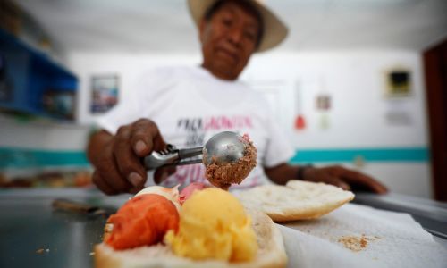 Meksyk, 23 czerwca 2017 r. Simon Sanchez, 77-letni sprzedawca lodów w Xonacatlan na obrzeżach Mexico City, nakłada kulki lodów na kromkę chleba, by zrobić „kanapkę z lodami” (powszechnie nazywaną tu Torta). Koszt 5-smakowej kanapki u Sancheza wynosi 0,77 dolarów. Fot. REUTERS/Edgard Garrido