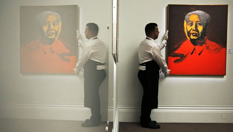 Pracownik pozuje ze sztuką artysty Andy'ego Warhola „Mao” w domu aukcyjnym Sotheby w Londynie (fot.REUTERS/Luke MacGregor)