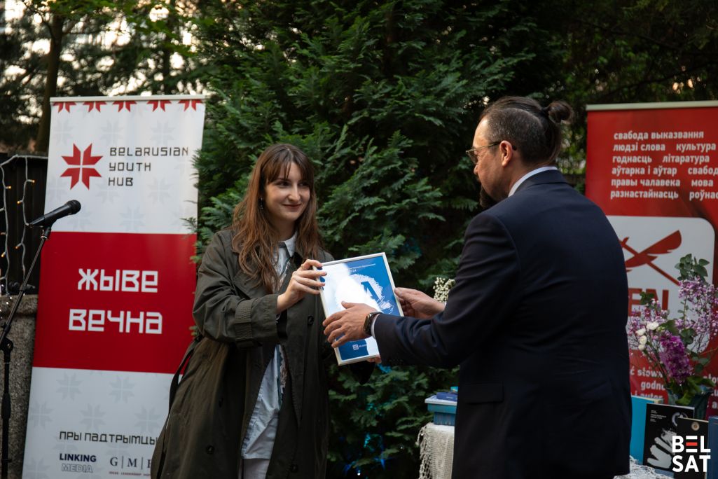 Мінулагодняя лаўрэатка прэміі паэтка Ганна Шакель уручае прэмію імя Наталлі Арсенневай прадстаўніку Сяргея Прылуцкага ў Беларускім моладзевым хабе. Варшава, Польшча. 24 траўня 2025 года. Фота: Белсат